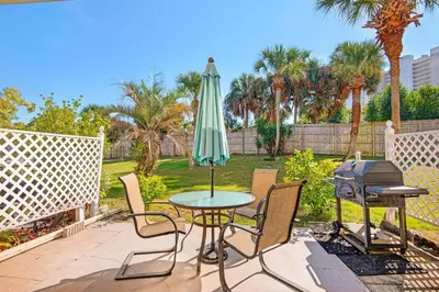 a patio with a table and an umbrella and a grill at Gulf Highlands 220 in Panama City Beach