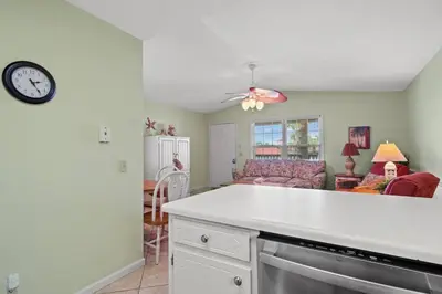 a kitchen and living room with a clock on the wall at Keep Palm and Carry On - 5 min walk to beach in Panama City Beach