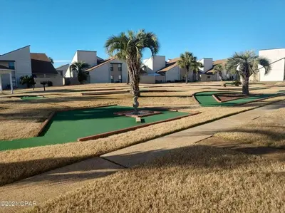 a golf course with palm trees and golf greens at Keep Palm and Carry On - 5 min walk to beach in Panama City Beach