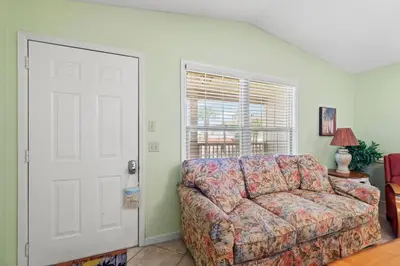 a living room with a couch and a window at Keep Palm and Carry On - 5 min walk to beach in Panama City Beach