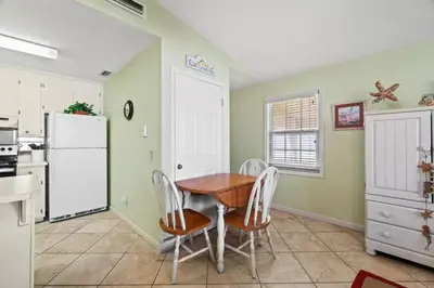a kitchen with a table and chairs and a refrigerator at Keep Palm and Carry On - 5 min walk to beach in Panama City Beach