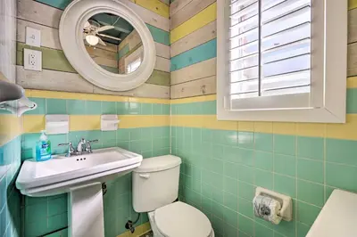 a bathroom with a toilet and a sink and a mirror at Steps to Sand, Pool Access Cozy Panama City Condo in Panama City Beach