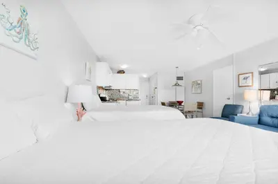 a white bedroom with a white bed and a blue couch at Top of the Gulf 208 in Panama City Beach