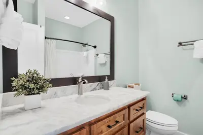 a bathroom with a sink and a toilet and a mirror at Moonlight Cottage in Panama City Beach