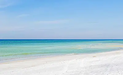a beach with a group of people in the water at Moonlight Cottage in Panama City Beach