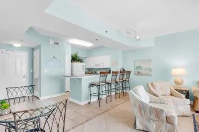 a living room with a table and chairs and a kitchen at Shores of Panama 1617 in Panama City Beach