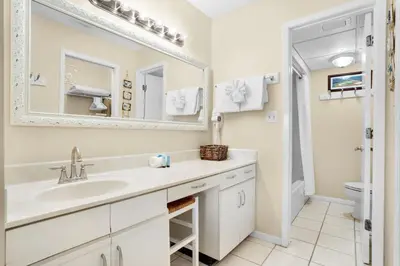 a white bathroom with a sink and a mirror at Edgewater Golf Villa 2010 in Panama City Beach