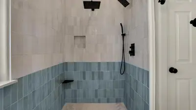 a bathroom with a shower with blue tiles at Lazy Days in Seacrest