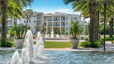 a fountain in front of a building with palm trees at Lazy Days in Seacrest
