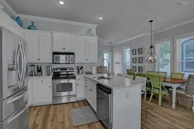 a kitchen with white cabinets and a table with chairs at The Real McCoy in Panama City Beach