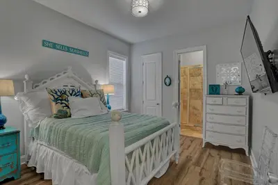a white bedroom with a bed and a dresser at The Real McCoy in Panama City Beach