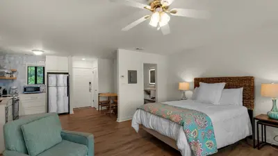 a bedroom with a bed and a chair and a kitchen at Hidden Beach 219 in Santa Rosa Beach
