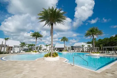 a pool at a resort with palm trees at Beach Abode in Watersound Beach
