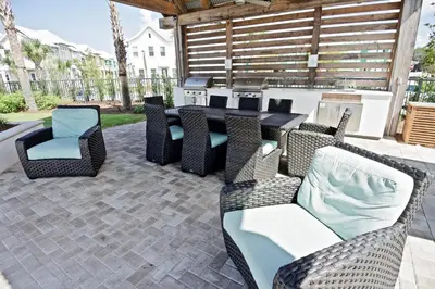 a patio with a table and chairs and a grill at Beach Abode in Watersound Beach