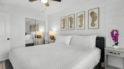 a white bedroom with a white bed and a mirror at Beachcrest 204 in Santa Rosa Beach
