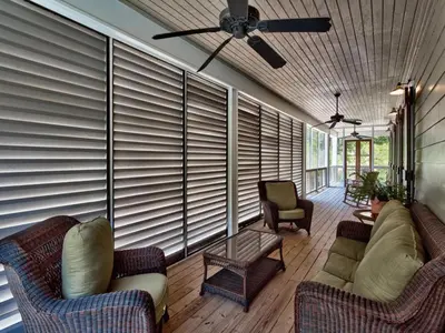 a screened in porch with couches and a ceiling fan at Southern Grounds in Santa Rosa Beach