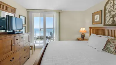 a bedroom with a bed with a television and a balcony at Beachcrest 304 in Santa Rosa Beach