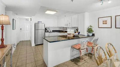 a kitchen with a counter and a refrigerator and chairs at Beachcrest 304 in Santa Rosa Beach