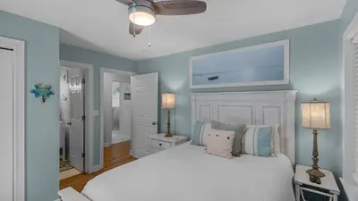 a bedroom with a white bed and a blue wall at La Pointe in Santa Rosa Beach