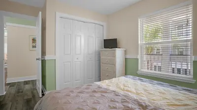a bedroom with a bed and a television and a window at Sea Turtle Pass in Santa Rosa Beach