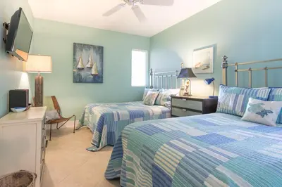 a bedroom with two beds and a flat screen tv at Villas At Sunset Beach A302 - Sunset Villa in Rosemary Beach