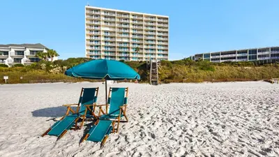 two beach chairs and an umbrella on the beach at Beachcrest 403 in Santa Rosa Beach