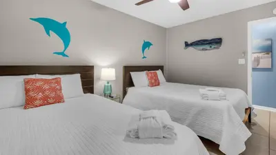 a bedroom with two beds and dolphins on the wall at Beachside Villas 513 in Santa Rosa Beach