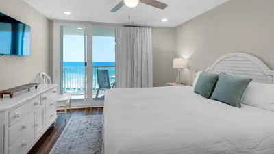a bedroom with a bed and a balcony with the ocean at Beachcrest 402 in Santa Rosa Beach