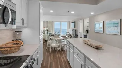 a kitchen with white counters and a table with chairs at Beachcrest 402 in Santa Rosa Beach