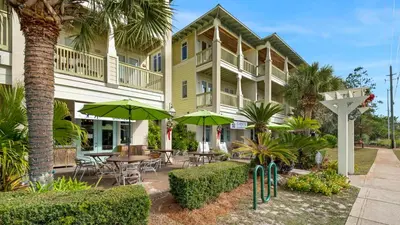 a building with tables and chairs and green umbrellas at Grand Isle 304 in Santa Rosa Beach