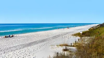 a beach with people sitting on the sand and the ocean at Beachcrest 404 in Santa Rosa Beach