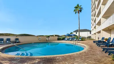 a swimming pool with chairs and a palm tree at Beachcrest 406 in Santa Rosa Beach
