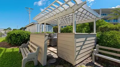 a white pergola over a table and two benches at Beachcrest 406 in Santa Rosa Beach