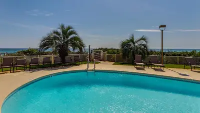 a large swimming pool with chairs and palm trees at Grand Playa 401 in Santa Rosa Beach