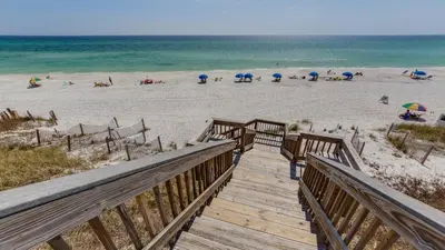 a wooden boardwalk leading to a beach with chairs and umbrellas at Grand Playa 401 in Santa Rosa Beach