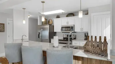 a kitchen with white cabinets and a table and chairs at Grand Playa 401 in Santa Rosa Beach