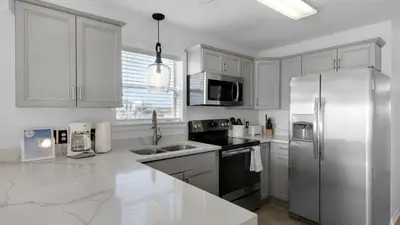 a kitchen with white cabinets and a stainless steel refrigerator at Beachside Villas 621 in Santa Rosa Beach