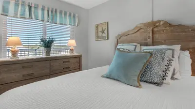 a bedroom with a bed with a wooden headboard and a window at Beachcrest 601 in Santa Rosa Beach