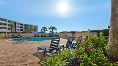a group of chairs sitting next to a swimming pool at Beachcrest 601 in Santa Rosa Beach