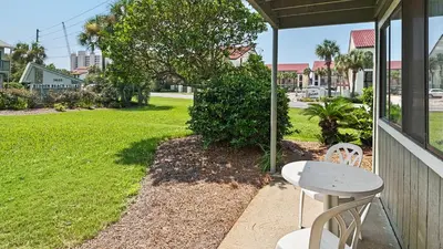a table and chairs on a porch with a lawn at Hidden Beach 101 in Santa Rosa Beach