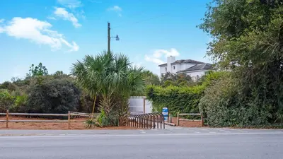 a street with a fence and a building in the background at Hidden Beach 101 in Santa Rosa Beach