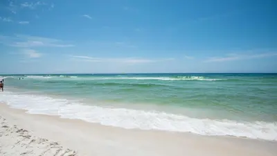 a beach with people walking on the sand and the ocean at Hidden Beach 117 in Santa Rosa Beach