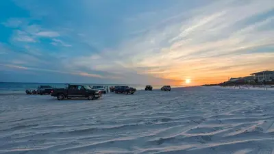 a group of cars parked on the beach at sunset at Hidden Beach 240 in Santa Rosa Beach