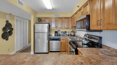a kitchen with wooden cabinets and a stainless steel refrigerator at Beachcrest 806 in Santa Rosa Beach