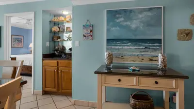 a living room with a table with a picture of the ocean at Beachcrest 902 in Santa Rosa Beach