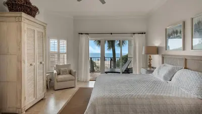 a white bedroom with a bed and a chair at Legacy 101 in Santa Rosa Beach
