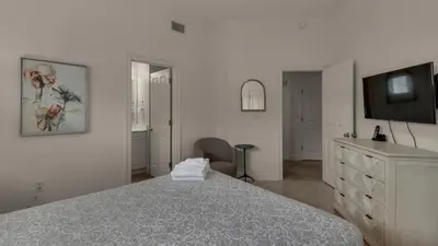 a white bedroom with a bed and a tv at Legacy 101 in Santa Rosa Beach