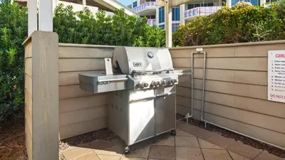 a barbecue grill sitting next to a fence at Beachcrest 903 in Santa Rosa Beach