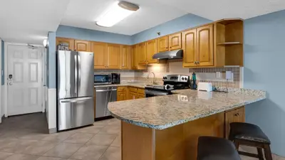 a kitchen with wooden cabinets and a stainless steel refrigerator at Beachcrest 904 in Santa Rosa Beach