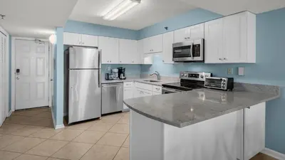 a kitchen with white cabinets and a stainless steel refrigerator at Beachcrest 906 in Santa Rosa Beach